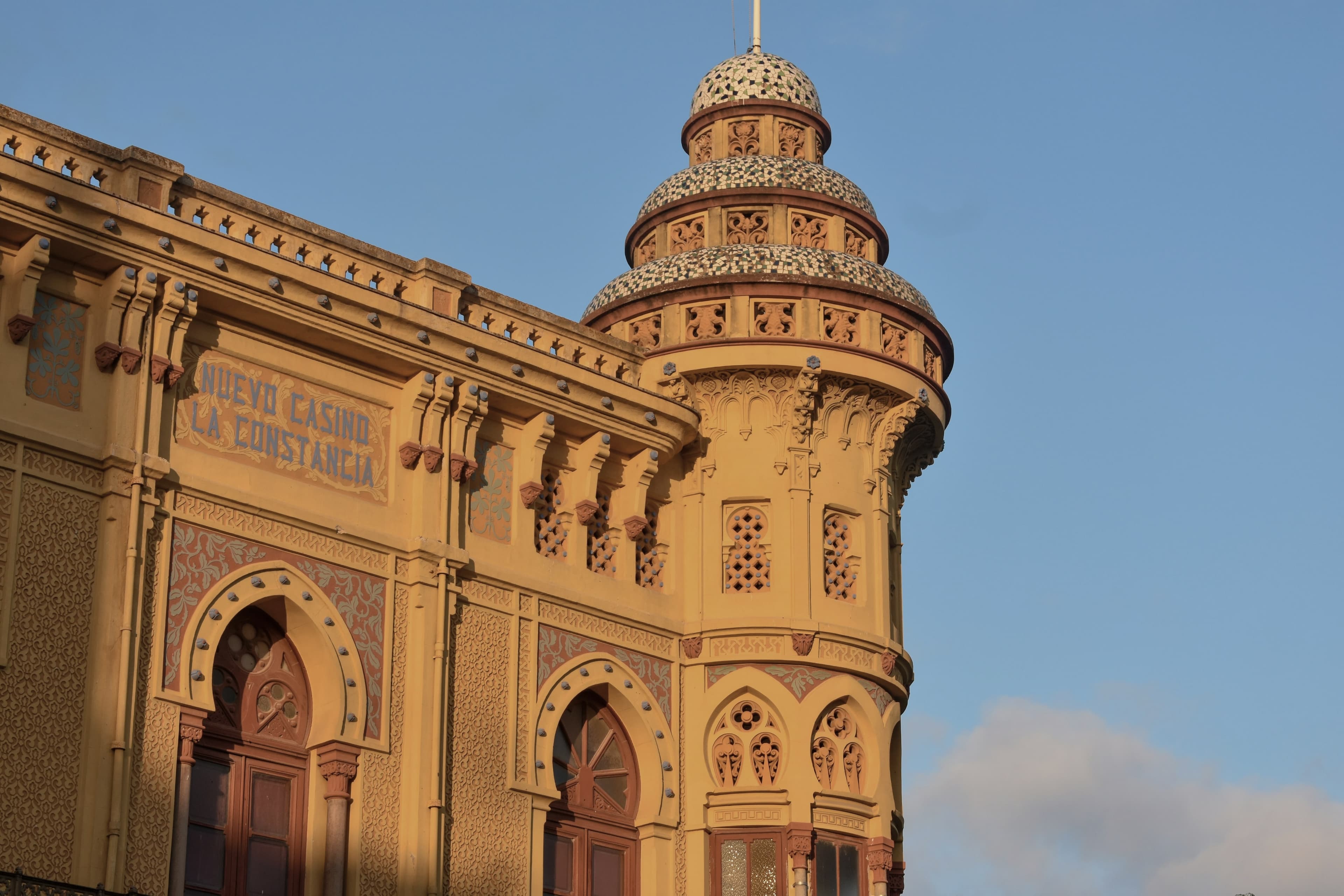 La fachada amarilla y la torre de azulejo del Casino La Constància, en Sant Feliu de Guíxols, a la luz del atardecer