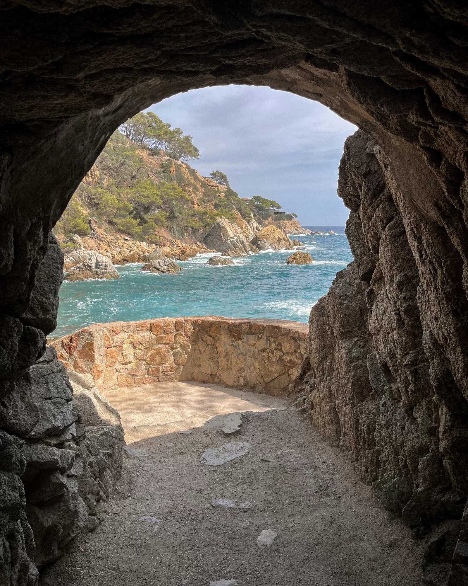 Un tramo del Camí de Ronda de la Costa Brava, con un arco de roca sobre una cala de agua turquesa