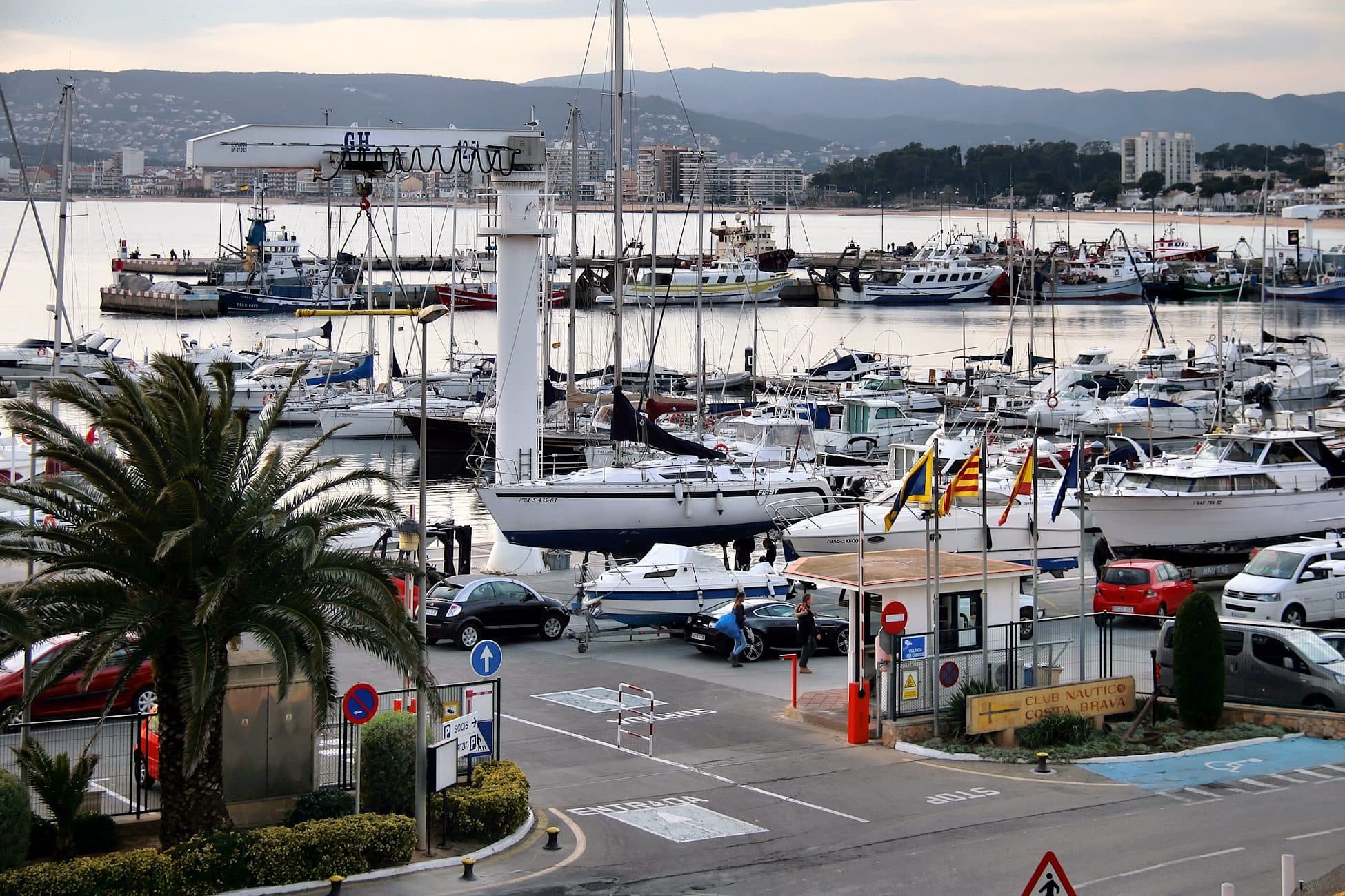 El puerto pesquero de Palamós al atardecer, con las barcas amarradas y la ciudad al fondo